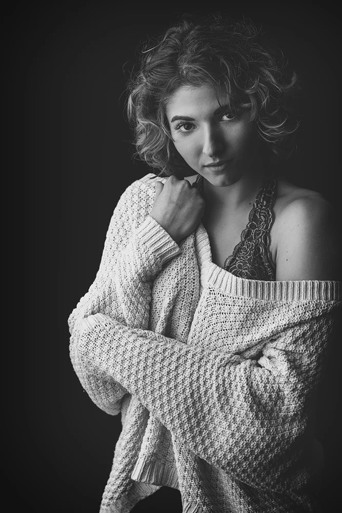 Informal black and white studio portrait of young woman in sweater