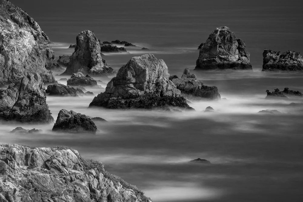 Fine art image of multiple boulders in Pacific Ocean taken using long Exposure photography techniques